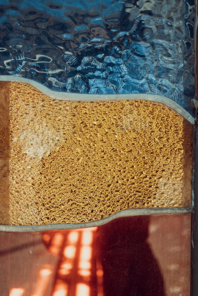 Abstract textured glass art with warm yellow and blue hues, creating a vibrant and artistic look.
