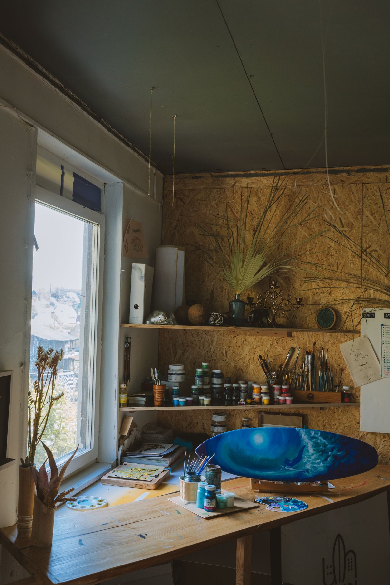 Art studio featuring paints, surfboard decor, and natural light.